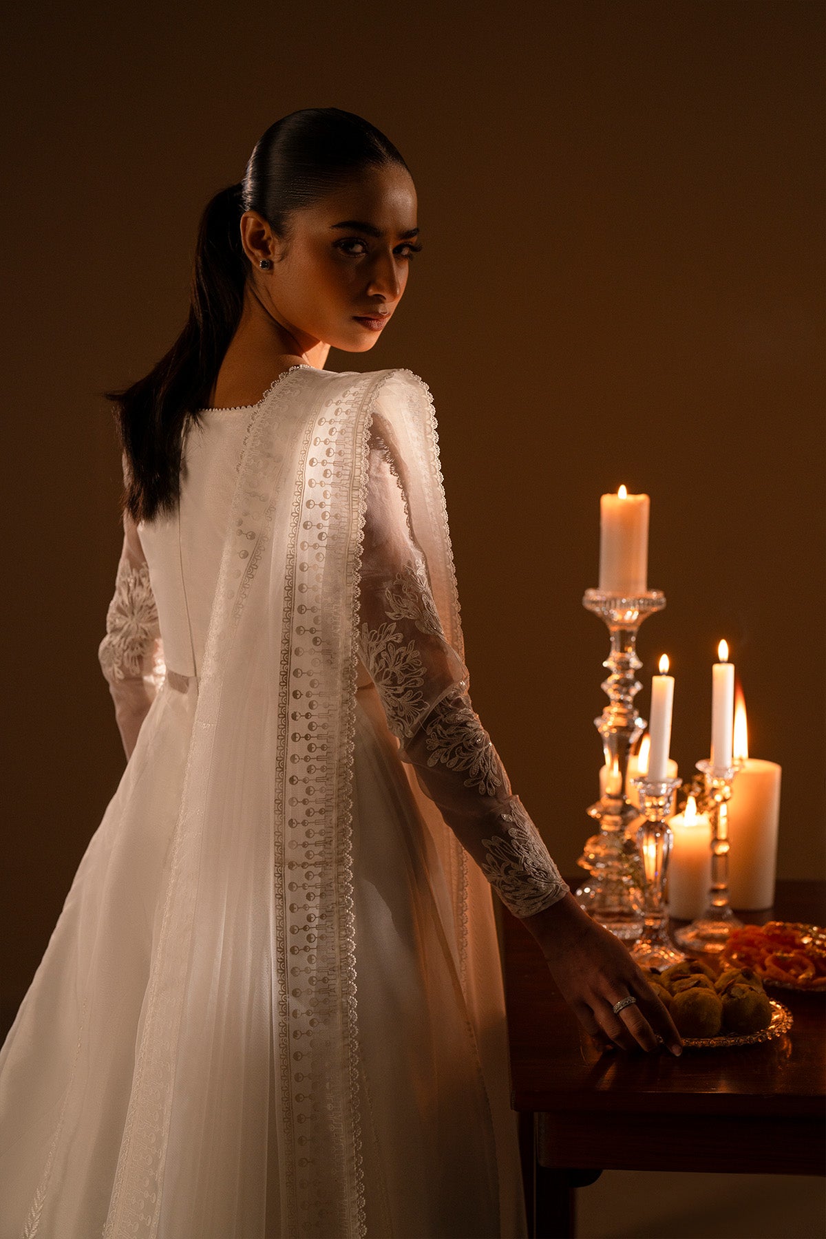 Model in a close back shot wearing a long flared pishwas with embroidered shirt and organza dupatta.