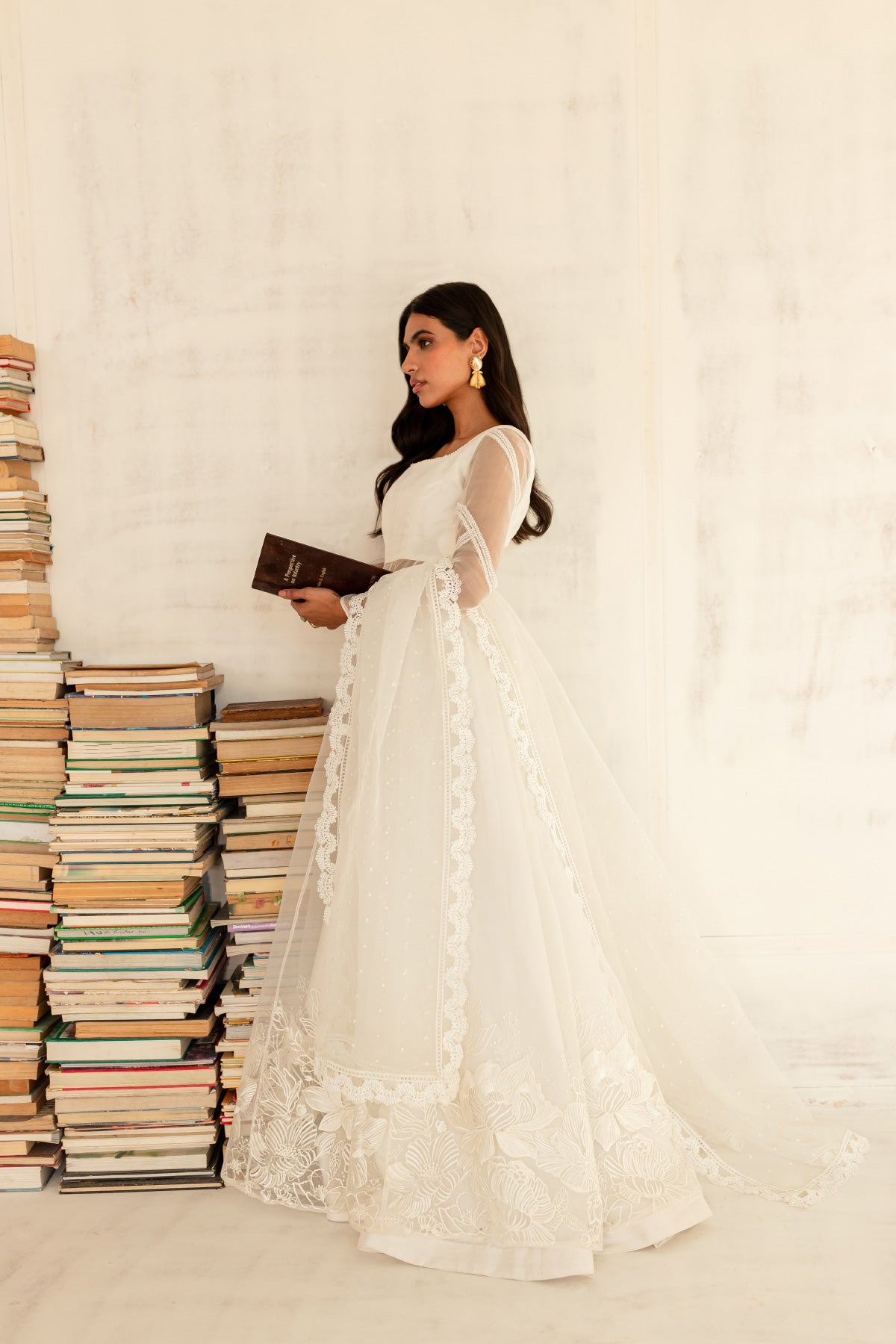 Model in a side view shot wearing a white organza shirt paired with an organza dupatta and a silk katan lehenga