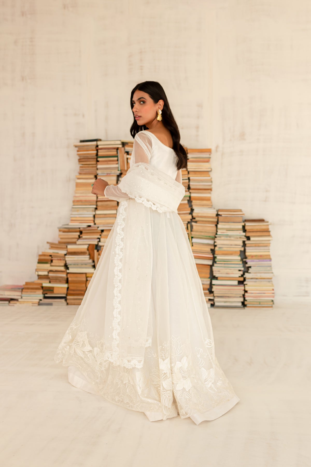 Model in a side view shot wearing a white organza shirt paired with an organza dupatta and a silk katan lehenga