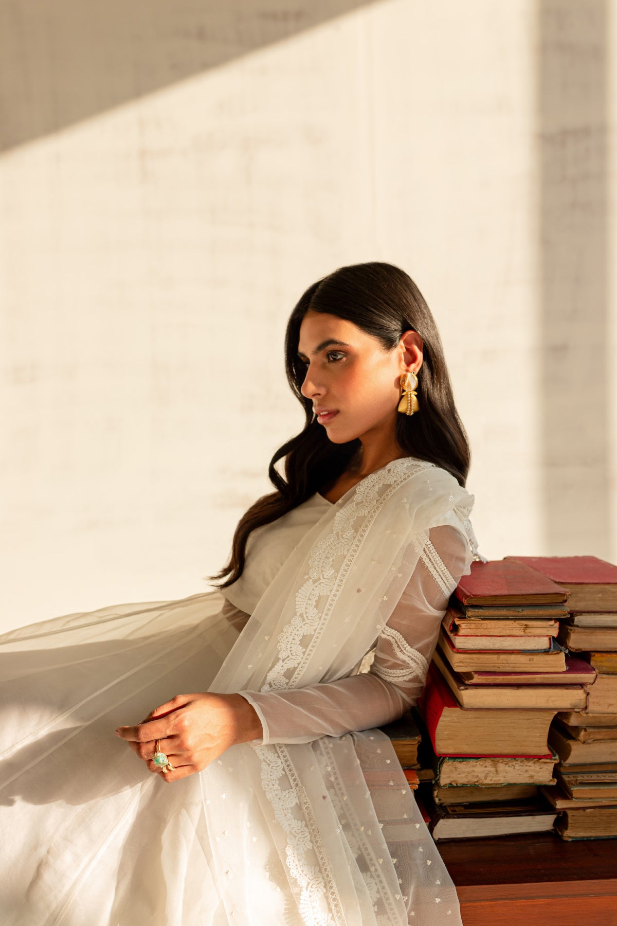 Model in a seated side view shot wearing a white organza shirt paired with an organza dupatta