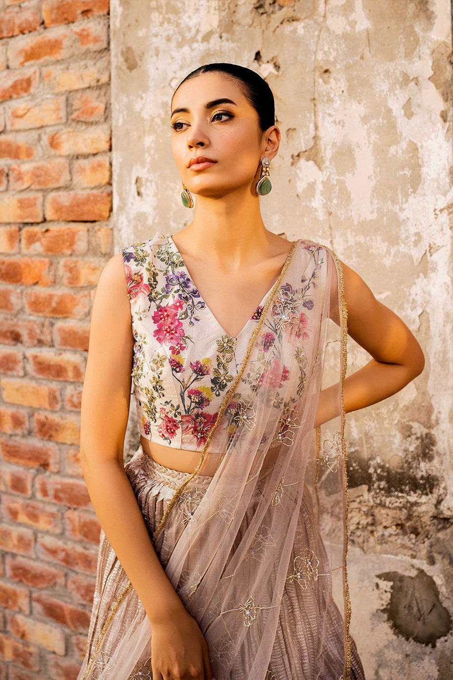 model in a closeup front shot wearing a formal white and rose gold masuri tissueblouse paired with a crushed tissue lehenga and a net embellished drape