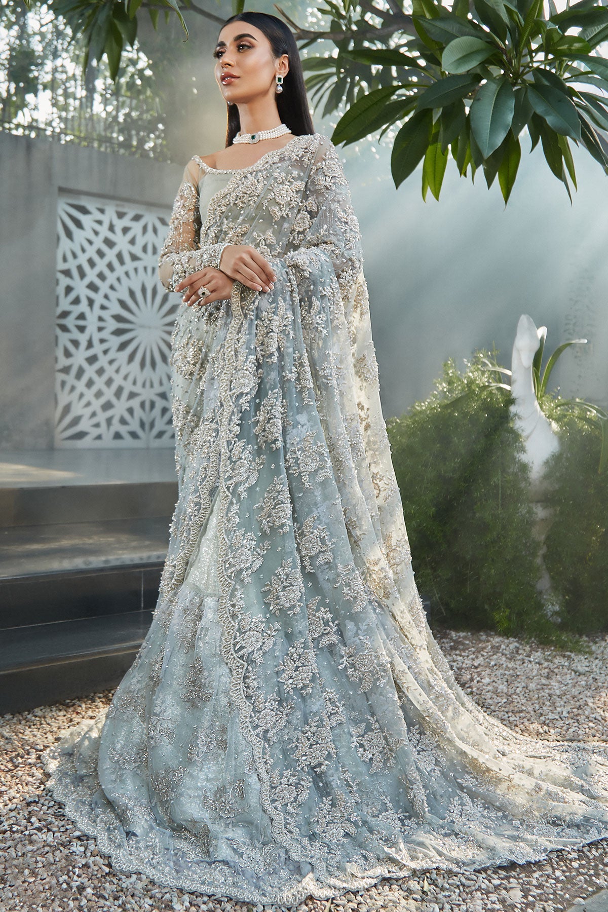 model in a side shot wearing blue bridal saree with net blouse and silk brocade lehenga