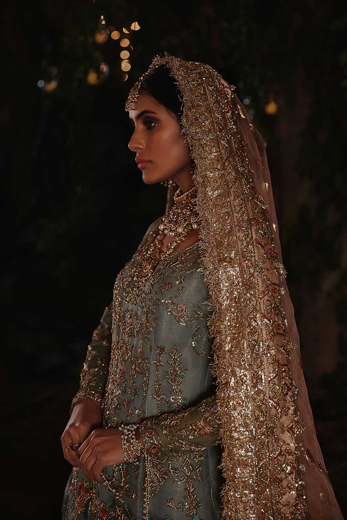 model in a side closeup shot wearing straight silk organza shirt in dusty blue color paired with silk organza gharara and organza zari dupatta 