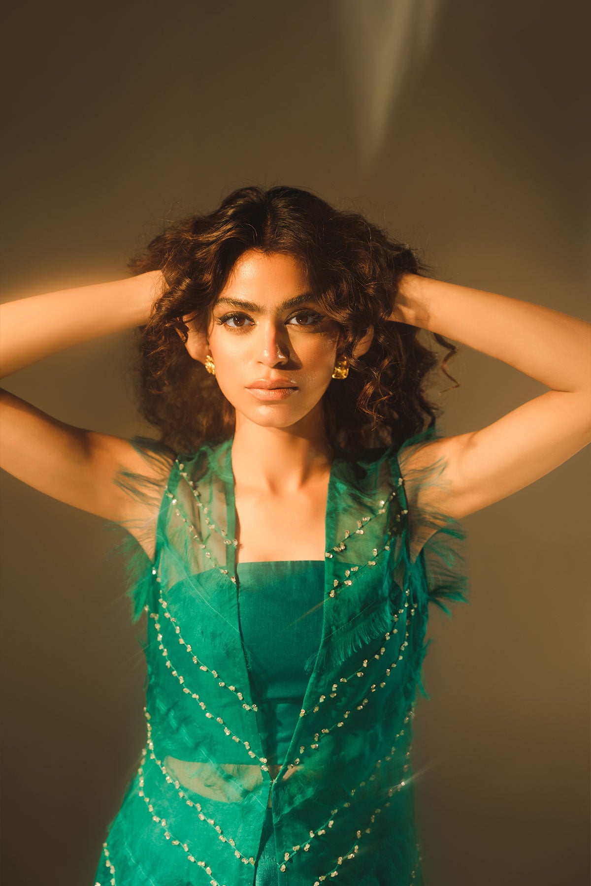 Model in a closeup shot wearing a emerald green silk organza front-open jacket paired with a bustier and tissue silk pants