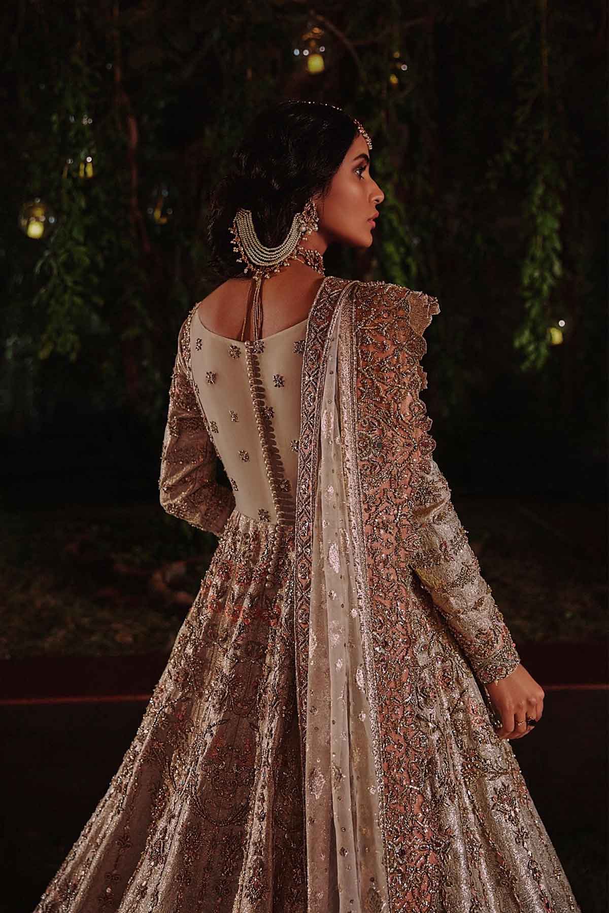 model in a back shot wearing ivory bridal silk brocade pishwas, with a lilac lehenga and an ivory dupatta