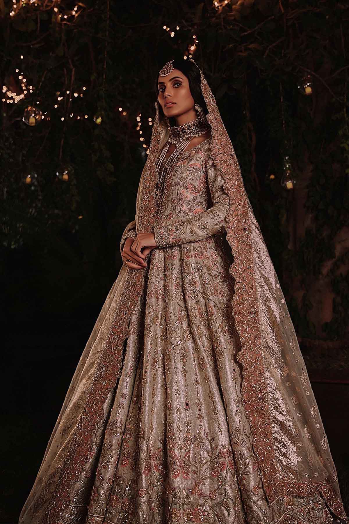 model in a side shot wearing ivory bridal silk brocade pishwas, with a lilac lehenga and an ivory dupatta