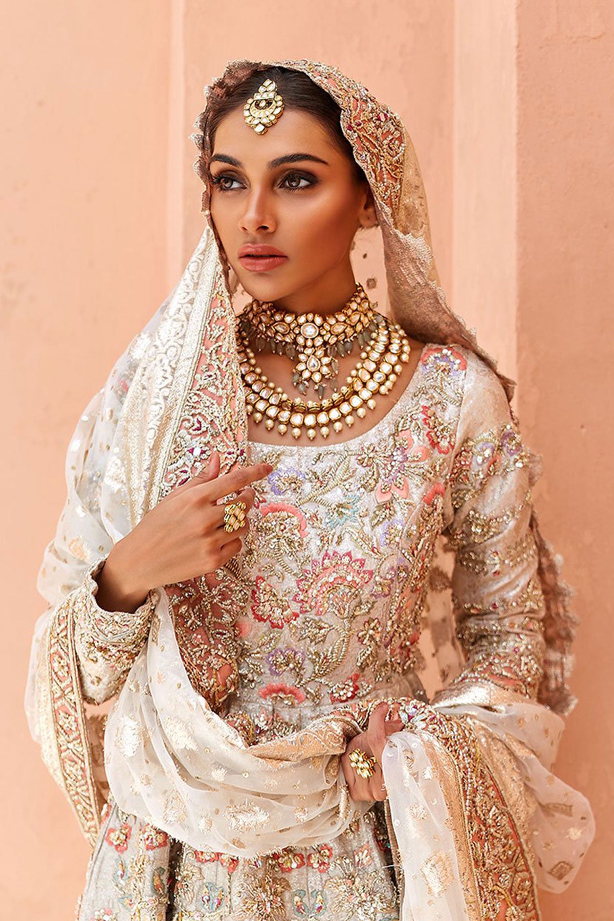 model in a closeup shot wearing ivory bridal silk brocade pishwas, with a lilac lehenga and an ivory dupatta