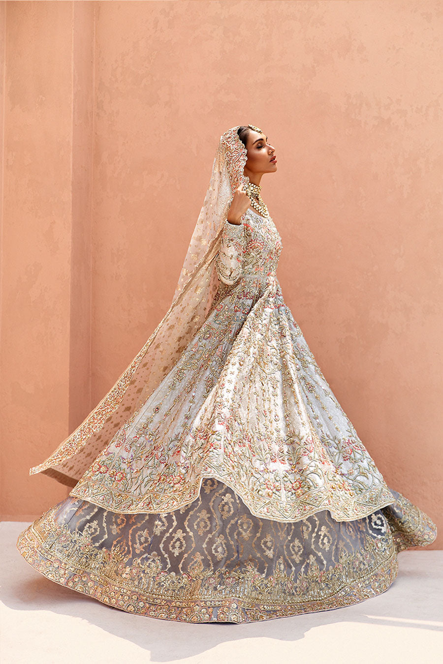 model in a side shot wearing ivory bridal silk brocade pishwas, with a lilac lehenga and an ivory dupatta