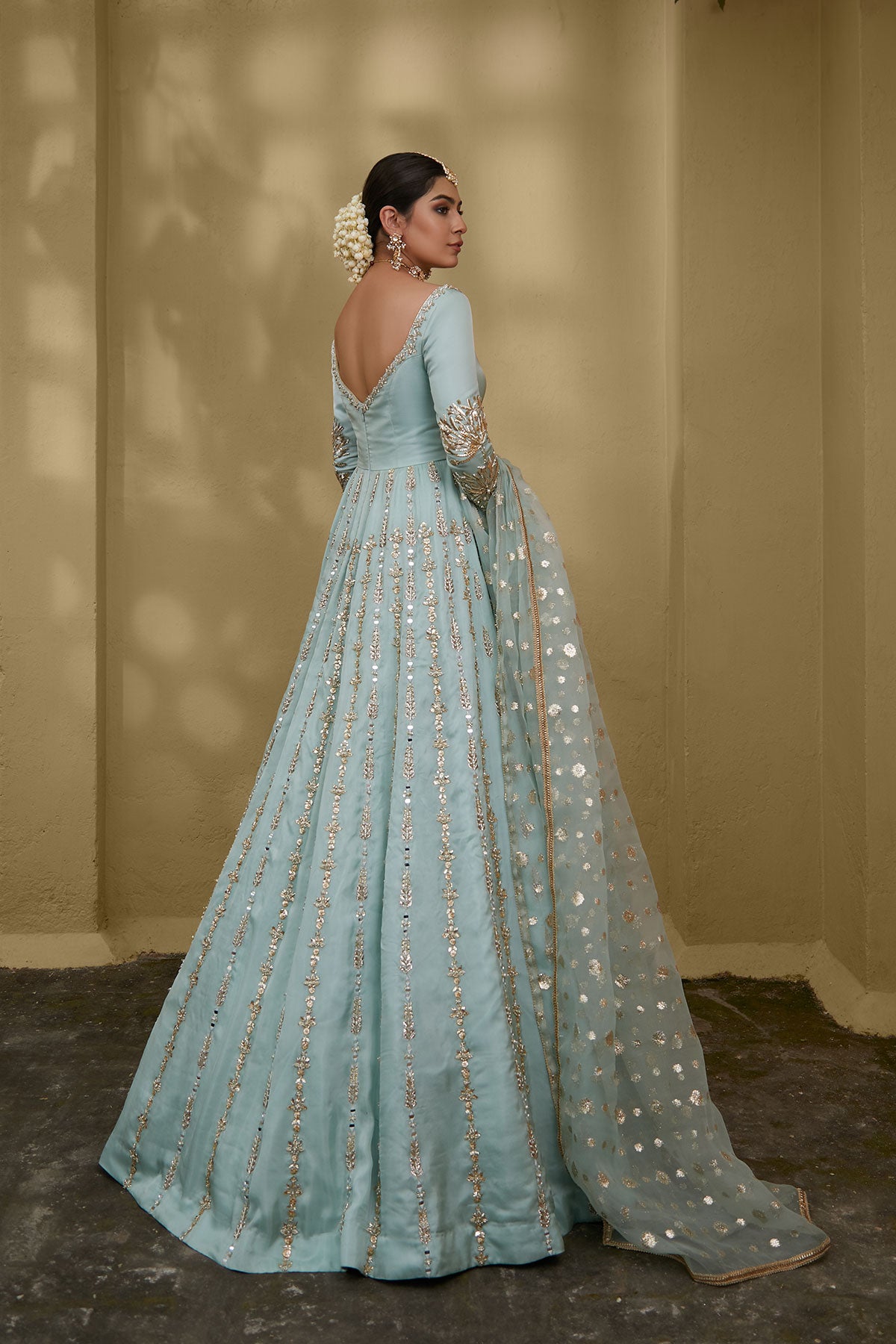 Model in a side shot wearing a formal light blue gown made of silk chiffon fabric paired with a blue organza zari dupatta