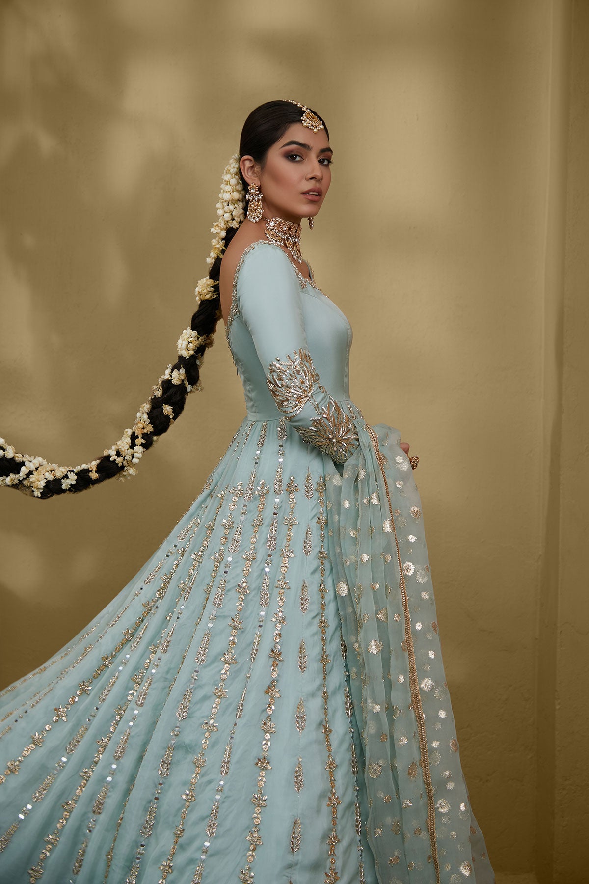 Model in a closeup side shot wearing a formal light blue gown made of silk chiffon fabric paired with a blue organza zari dupatta