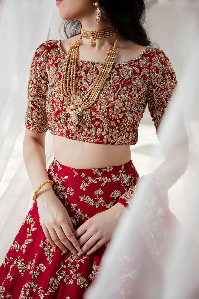 Model in a front closeup shot wearing maroon raw silk bridal lehnega paired with organza dupatta and silk brocade choli