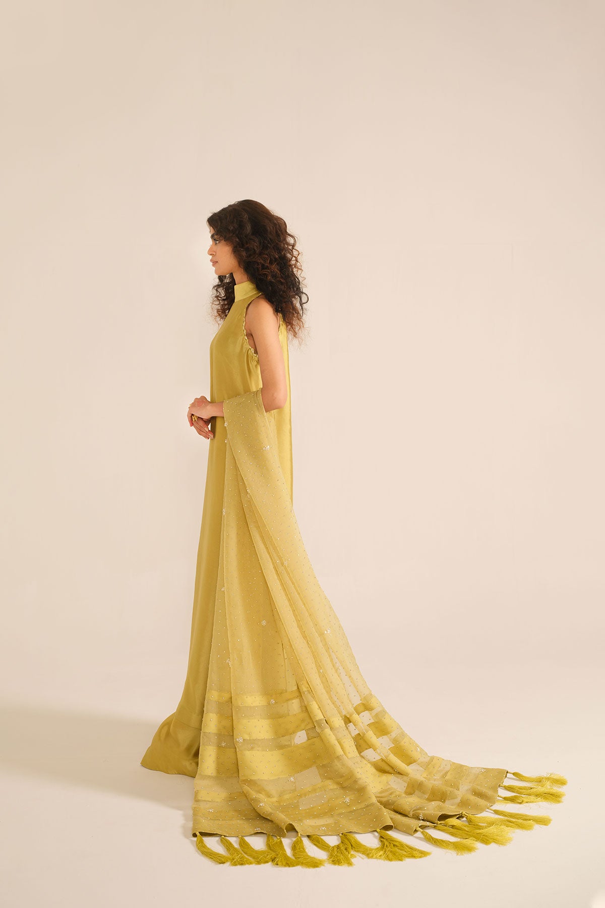 Model in a back closeup shot wearing mustard tissue silk shirt with a halter neckline paired with flared pants and silk organza dupatta 