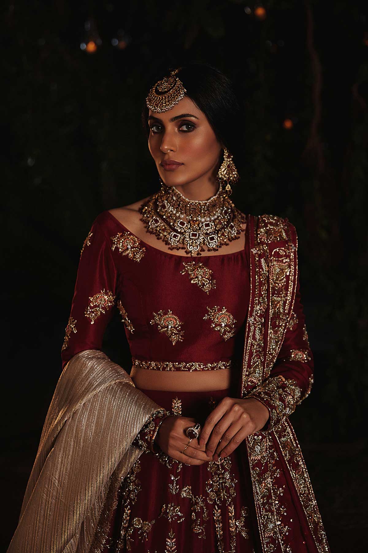 model in a closeup shot wearing red bridal lehenga choli in raw silk fabric paired with silk organza dupatta