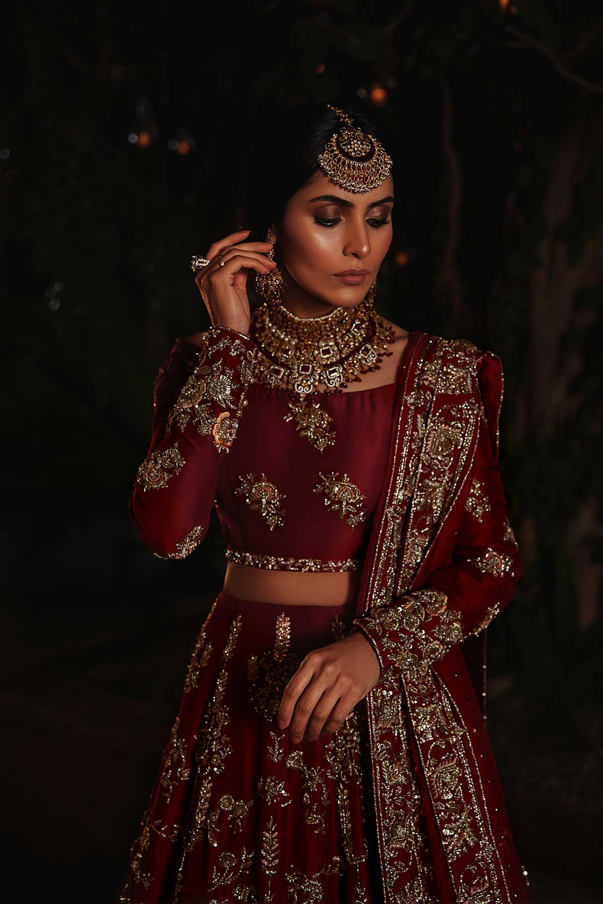 model in a closeup shot wearing red bridal lehenga choli in raw silk fabric paired with silk organza dupatta