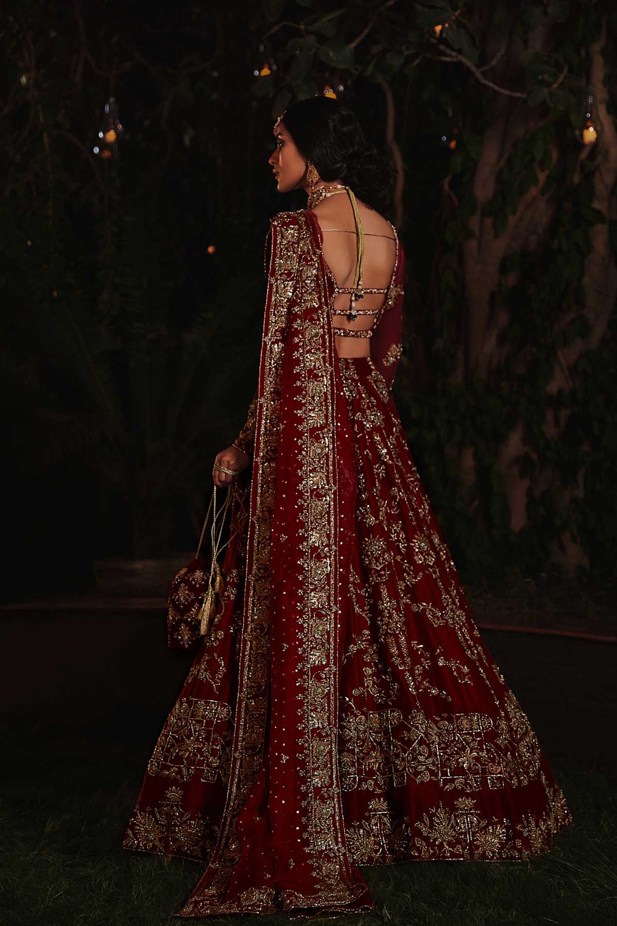 model in a back shot wearing red bridal lehenga choli in raw silk fabric paired with silk organza dupatta