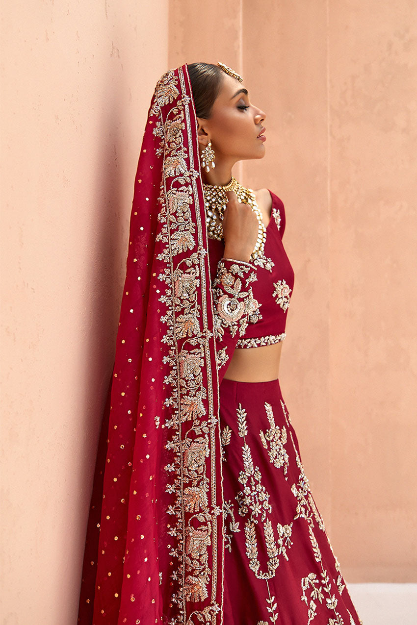 model in a side closeup shot wearing red bridal lehenga choli in raw silk fabric paired with silk organza dupatta