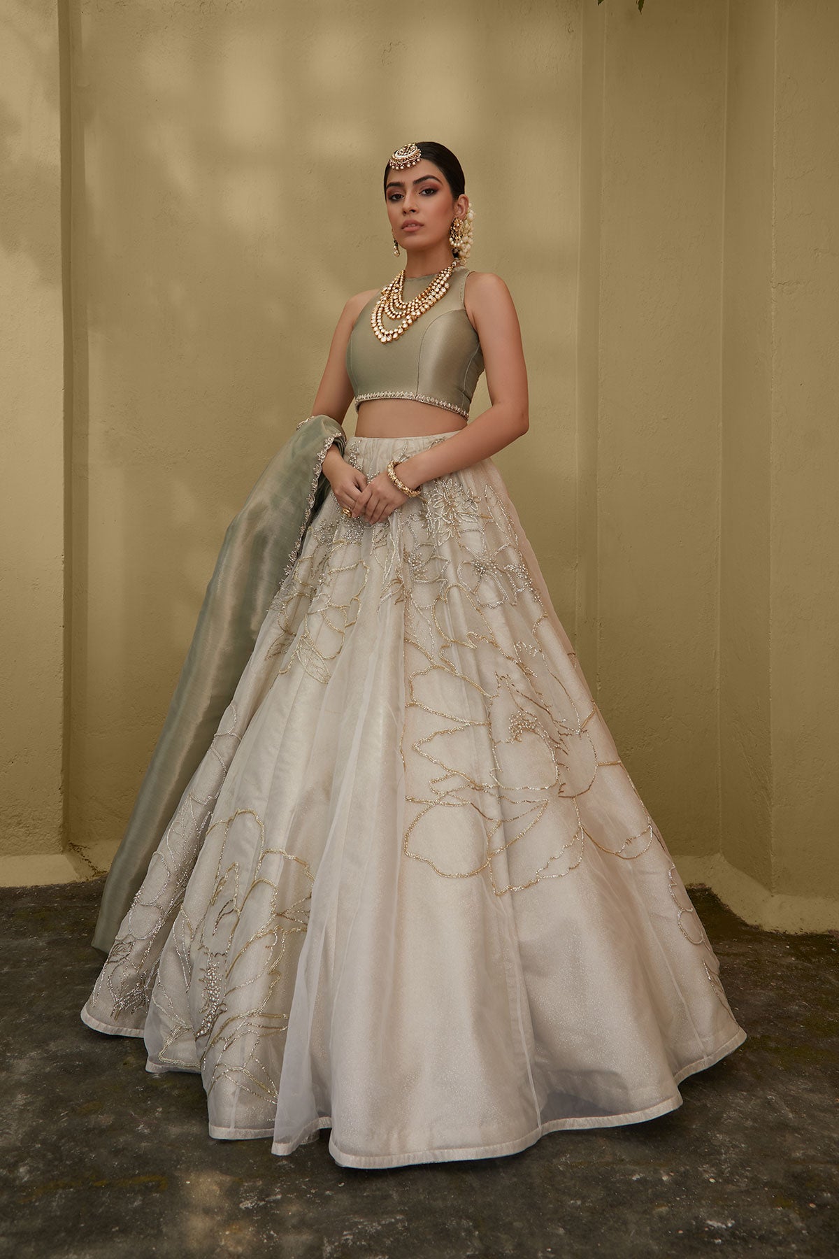 Model in a front shot wearing white organza skirt paired with green tissue blouse and an embroidered tissue dupatta