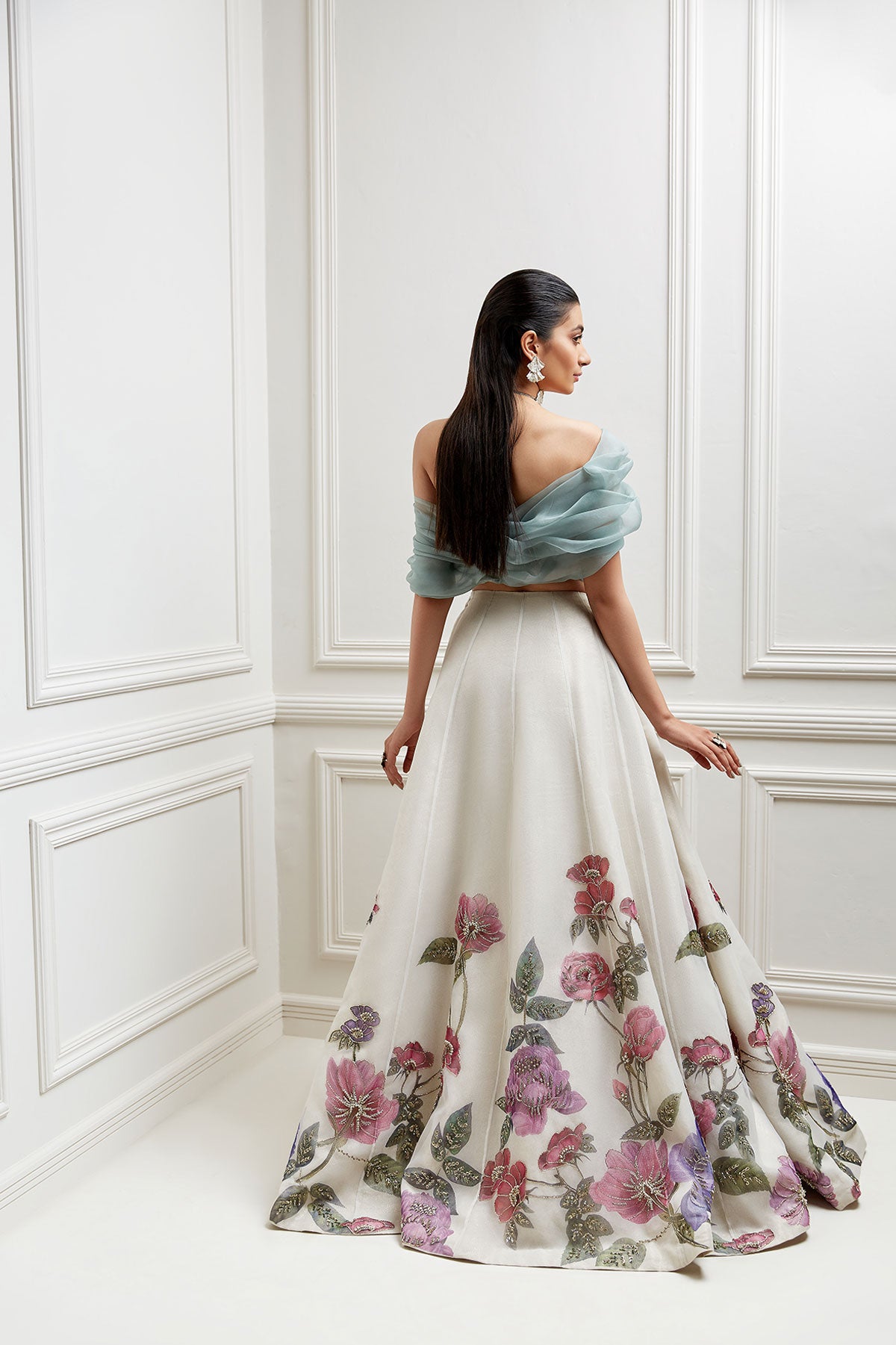 model in a back shot wearing ivory, hand-painted floral organza skirtp aired with an off-shoulder organza blouse